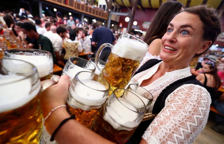 Una mesara lleva nueve tarros de cervezas a una mesa de comensales de la tienda “Paulaner”, en la inauguración de la edición 189 del tradicional festival de cerveza Oktoberfest en la capital bávara Múnich