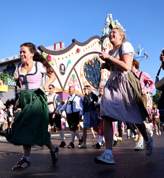 Asistentes observan el desfile inaugural de la edición 189a. del tradicional festival de cerveza. Abajo, niños y adultos se divierten en un carrusel del área de juegos mecánicos