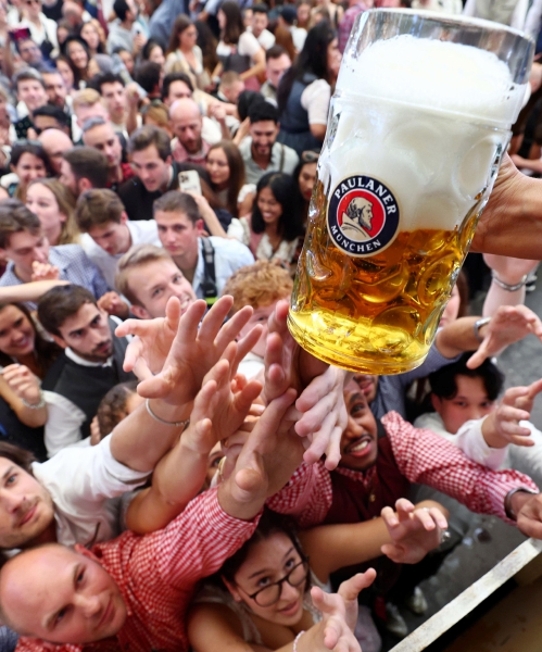 Personas con trajes típicos de la región bávara chocan sus tarros durante la jornada inaugural del esperado evento anual del Oktoberfest, el festival de la cerveza en Múnich, Alemania, que este año espera alrededor de 6 millones de visitantes durante dieciséis días de festejos