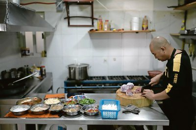 Li Ming prepara comida en el restaurante “Nueve y media”, propiedad de su hijo y ubicado en Ciudad de México. A la derecha, un hombre de China recibe una ración de avena, mientras espera a que su solicitud de asilo sea procesada en México, luego de cruzar la frontera