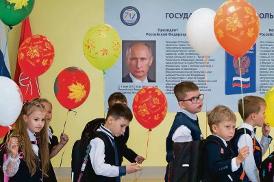 Alumnos pasan junto a un cartel con la imagen del presidente ruso, Vladimir Putin, tras la ceremonia de inicio del año escolar en San Petersburgo