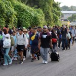 Migrantes caminan en una caravana, en el municipio de Tapachula, estado Chiapas, México, anteayer. A la izquierda, Robert Vivar (derecha), de la Iglesia Episcopal de San Diego, habla con un grupo de migrantes liberados por la Patrulla Fronteriza en California, Estados Unidos, el 26 de febrero