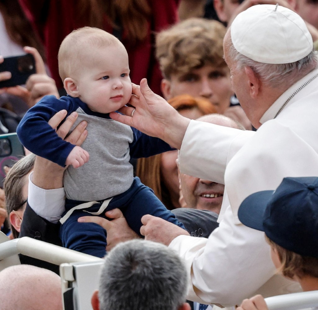 El papa Francisco acaricia a un bebé a su llegada para presidir la audiencia general semanal en la Plaza de San Pedro, el miércoles