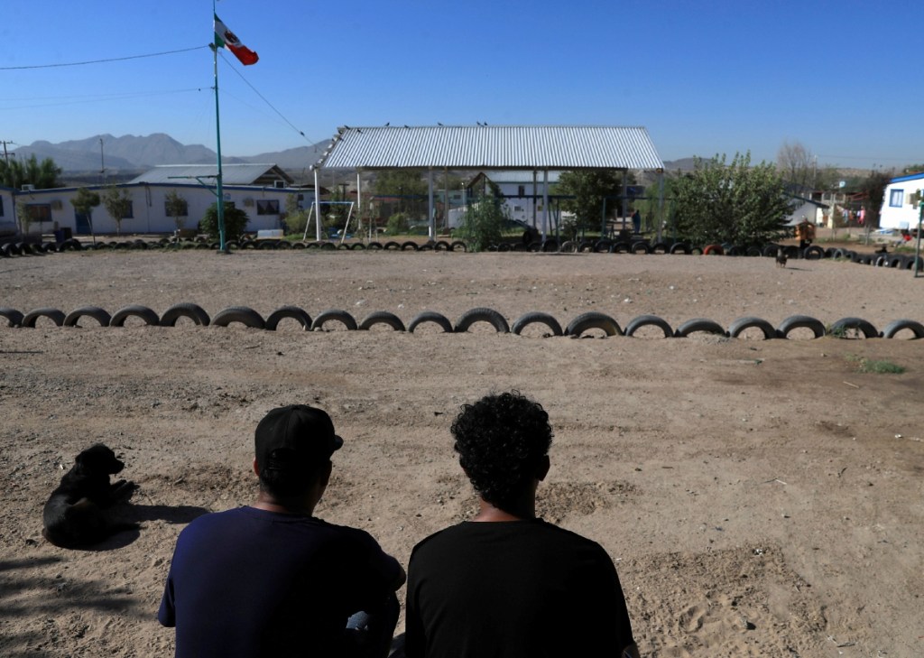 Migrantes de Honduras descansan frente a una cancha, en espera de resolver su situación migratoria, en un albergue en Ciudad Juárez