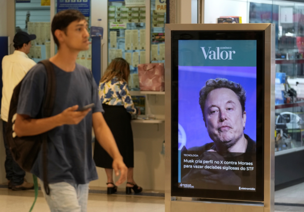 Un peatón pasa junto a una foto de Elon Musk en Brasilia, Brasil