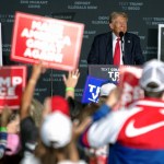 Donald Trump habla durante un mitin en Gaylord Rockies and Resort en Aurora, Colorado. A la izquierda, un simpatizante del Trump muestra unos anillos con el rostro de aquél en el acto de campaña en la misma ciudad