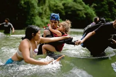 Una familia venezolana atraviesa un río cerca de Bajo Chiquito, Panamá, después de cruzar el Tapón de Darién, Colombia, rumbo a Estados Unidos