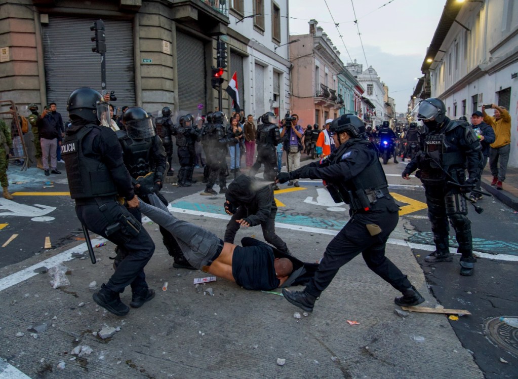 Arriba, un hombre participa en la protesta, en Quito, contra el gobierno de Daniel Noboa. A la izquierda, una persona es detenida por la policía durante la manifestación, debido a la situación energética en el país y los cortes de electricidad programados a escala nacional