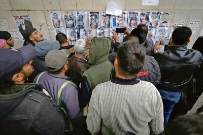 Sirios examinan fotografías colocadas en una pared del hospital de Al-Mojtahed de Damasco, en busca de familiares o conocidos entre los prisioneros que fueron hallados en cárceles del depuesto régimen de Siria