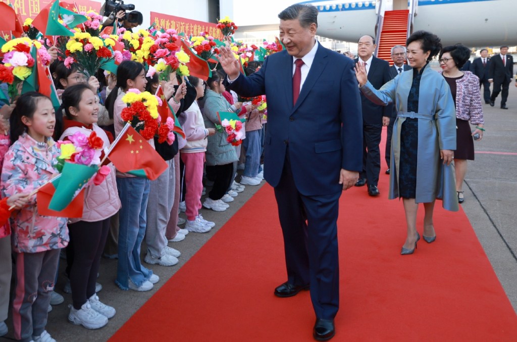 El presidente chino, Xi Jinping, y su esposa, Peng Liyuan, saludan a la multitud que los recibe en Macao