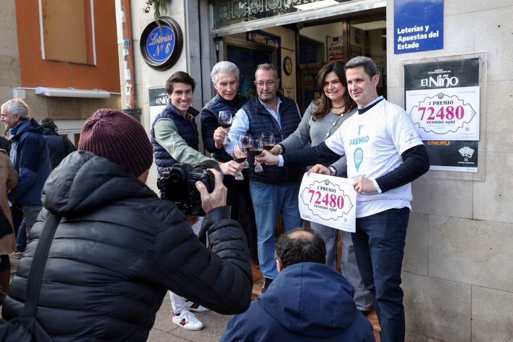 Personas posan en el lugar donde se vendió "El Gordo" de la Lotería de Navidad en España (Foto de EFE)