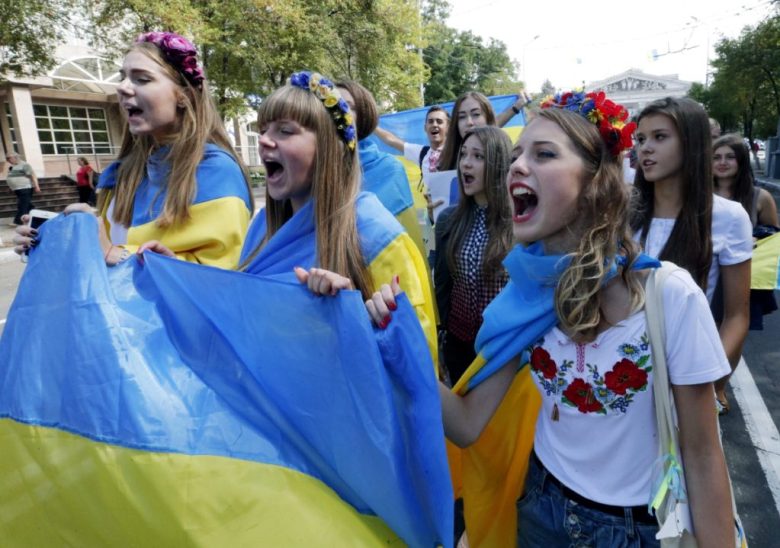 El presidente ruso, Vladimir Putin, saluda en la cumbre de la APEC, en 2017, a su entonces colega estadounidense, Donald Trump. A la izquierda, estudiantes ucranianos protestan contra Putin en Mariupol en 2014