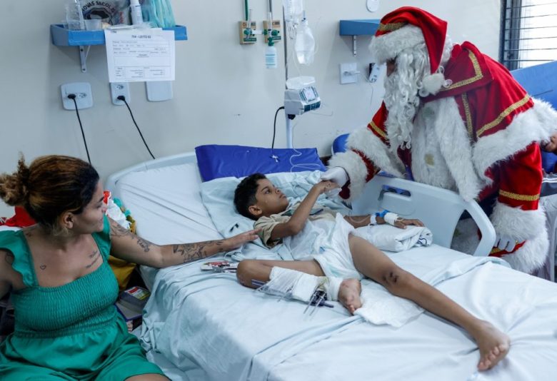 Santa saluda a un niño durante una jornada navideña de visita a niños hospitalizados. A la derecha, abraza a un bebé