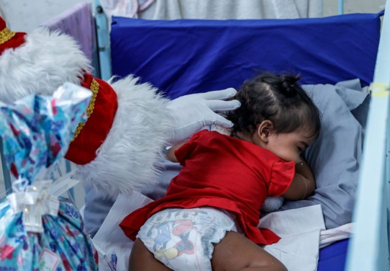 Un hombre disfrazado de Santa Claus acaricia a una pequeña paciente del Hospital Municipal Souza Aguiar, en Río de Janeiro, Brasil