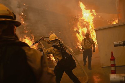 Debajo, bomberos trabajaban ayer a toda prisa para controlar un incendio forestal de rápida propagación en las colinas de Los Ángeles, California, en donde habitan muchas celebridades