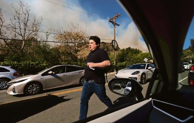 Sobre estas líneas, un residente de Los Ángeles, California, trata de alejarse de las llamas que avanzaban con rapidez en el área de Pacific Palisades