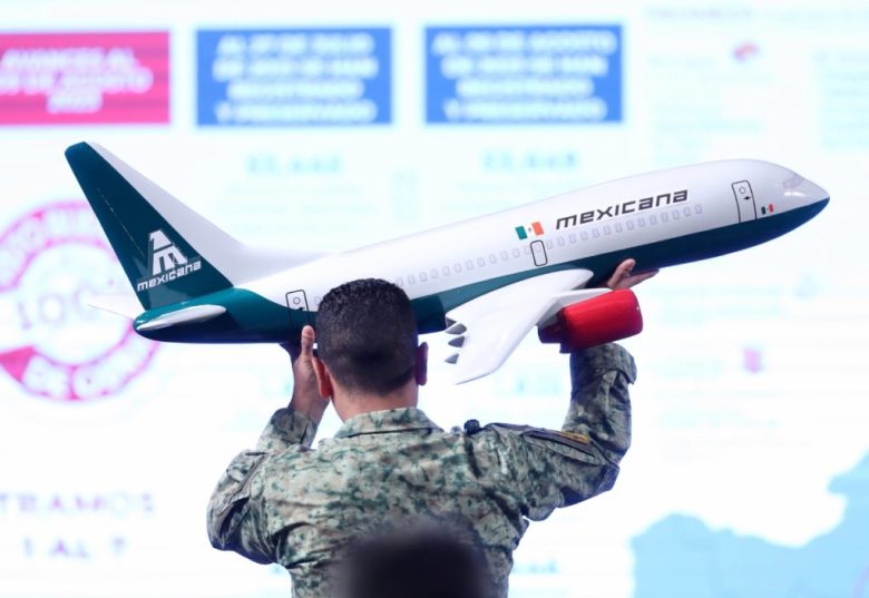 Un soldado sostiene la maqueta de un avión de Mexicana. La aerolínea estatal enfrenta deudas, cancelación de rutas y una baja ocupación