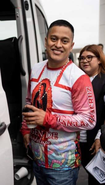 Arturo Zacarías, con una camisera con la imagen de la Virgen de Guadalupe, sonríe antes de subir a un minibús a su llegada al aeropuerto internacional General Heriberto Jara en Veracruz, el 24 de enero de 2025, días después de su liberación por parte de los rebeldes hutíes de Yemen, que habían secuestrado el mercante en el que navegaba el Galaxy Leader en el Mar Rojo. A la izquierda, el abrazo de su prometida, Evelyn Tinoco