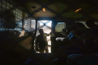 Vigilancia en la frontera con México vista desde el lado de Estados Unidos, en San Diego, California. A la izquierda, un agente de la Patrulla Fronteriza de Estados Unidos da instrucciones a unos detenidos