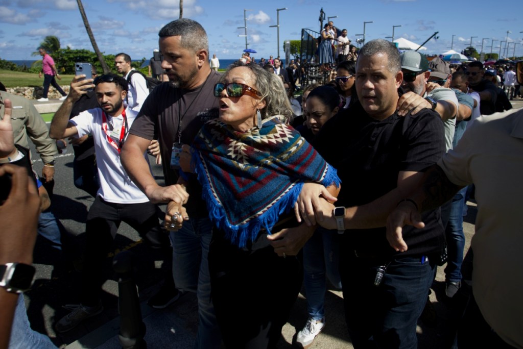 Seguidores del senador independiente puertorriqueño Eliezer Molina son detenidos ayer, antes de la ceremonia. A la derecha, la gobernadora Jenniffer González, y su esposo, José Jovin Vargas, rezan en la iglesia de las Siervas de María, en San Juan, ayer antes del acto protocolario