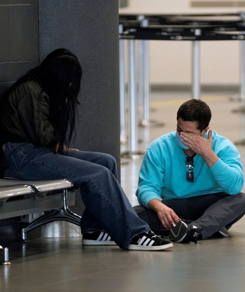 Dos migrantes colombianos deportados por Estados Unidos, sentados en el aeropuerto El Dorado tras regresar a Bogotá. A la derecha, otra migrante deportada