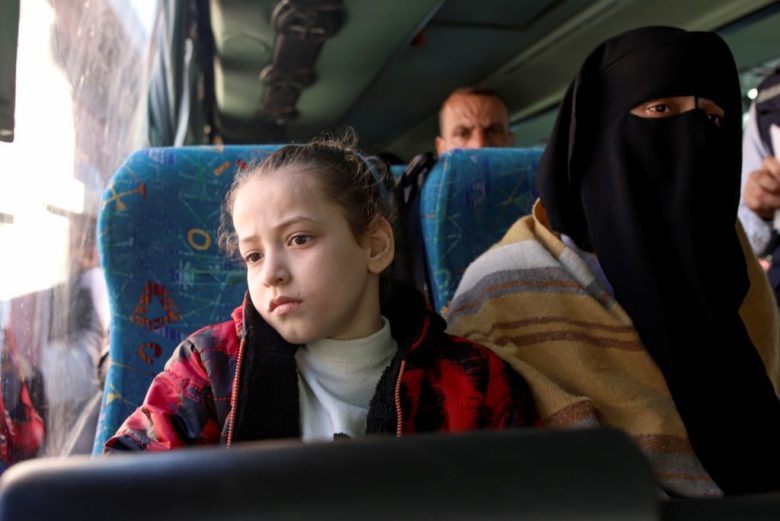 Una niña palestina herida y un acompañante aguardan para cruzar el paso fronterizo de Rafah a Egipto, en el primer día de desalojos médicos en meses, en Jan Yunis. A la derecha, un palestino y sus dos hijos esperan su turno para realizar el primer cruce médico de la tregua