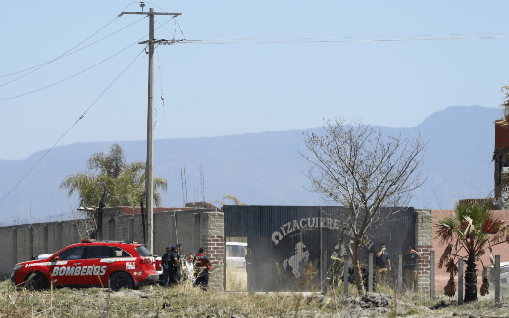 Integrantes de la fiscalía estatal y bomberos resguardan la entrada del rancho Izaguirre, en el municipio de Teuchitlán, Jalisco, ayer martes