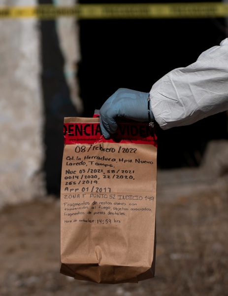 Un técnico forense con una bolsa con evidencias recolectadas de un terreno considerado como un sitio de exterminio, en Nuevo Laredo