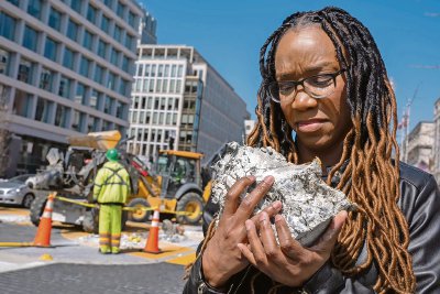 Starlette Thomas, de Bowie, Myreland, sostiene un trozo de pavimento de la plaza “Black Lives Matter”. A la derecha, un obrero retira uno de los bolardos colocados por el Ayuntamiento para convertir la plaza en un espacio peatonal. Ahora la plaza será para conmemorar los 250 años de la ciudad