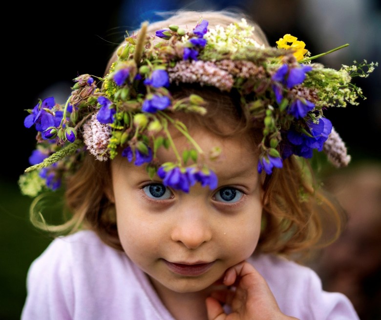 Una niña porta una corona hecha de flores durante las celebraciones por el Día de San Juan y el solsticio de verano en Kernave, a unos 35 kilómetros (22 millas) al noroeste de la capital, Vilna, Lituania, el lunes 23 de junio de 2025. (AP Foto/Mindaugas Kulbis)
