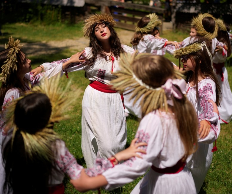 Niñas con coronas de flores bailan durante un evento inspirado en tradiciones precristianas, en las que hadas, llamadas "Sanziene" en rumano, bajan a la Tierra en el solsticio de verano como símbolo de fertilidad, en Bucarest, Rumania, el martes 24 de junio de 2025. (AP Foto/Andreea Alexandru)