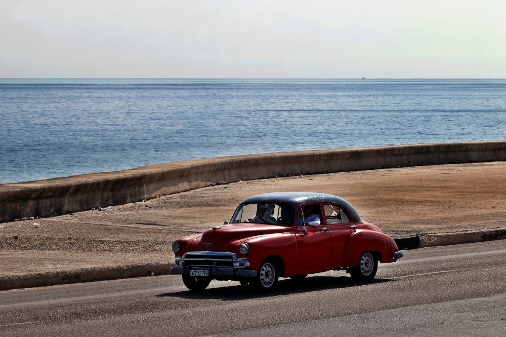Un auto pasa junto al malecón en La Habana, Cuba