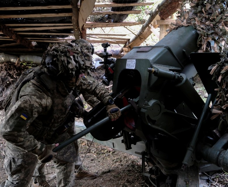 Equipo de doctores estabiliza a un soldado ucraniano, en un punto médico de Donetsk. A la izquierda, miembros del ejército de Ucrania se preparan para derribar objetivos rusos durante uno de los ataques
