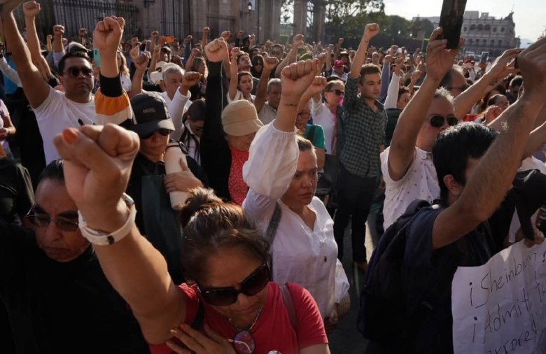 Una joven que se manifestaba ayer frente al Palacio de Gobierno de Morelia, por el crimen del alcalde de Uruapan es detenida al igual que otros jóvenes, algunos de los cuales irrumpieron en el recinto y causaron destrozos. A la izquierda, otros manifestantes por el asesinato de Carlos Manzo