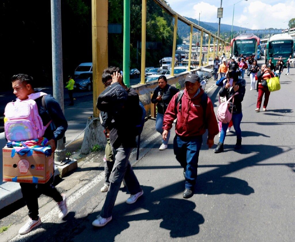 Pasajeros caminan por la autopista México-Toluca debido al bloqueo en el peaje, ayer lunes. Transportistas y agricultores exigen seguridad y precios justos a sus productos
