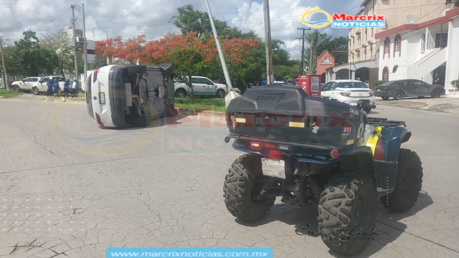Un vehículo blanco aparece volcado sobre su costado en medio de una calle, mientras una patrulla tipo cuatrimoto está en primer plano y varias personas observan a distancia.